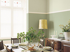 Traditional dining setting with a pop of green on the walls yellow lamp plants and wooden table